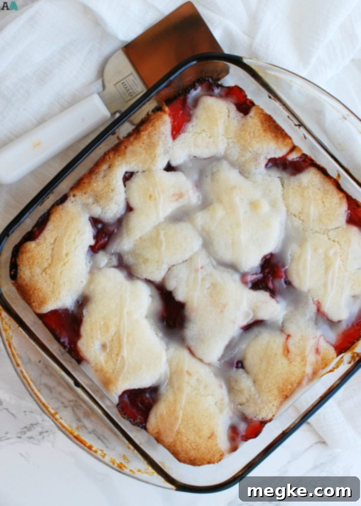 A close-up of a warm, freshly baked vegan cherry cobbler, showing the golden cake and vibrant cherry filling, ready to be served.