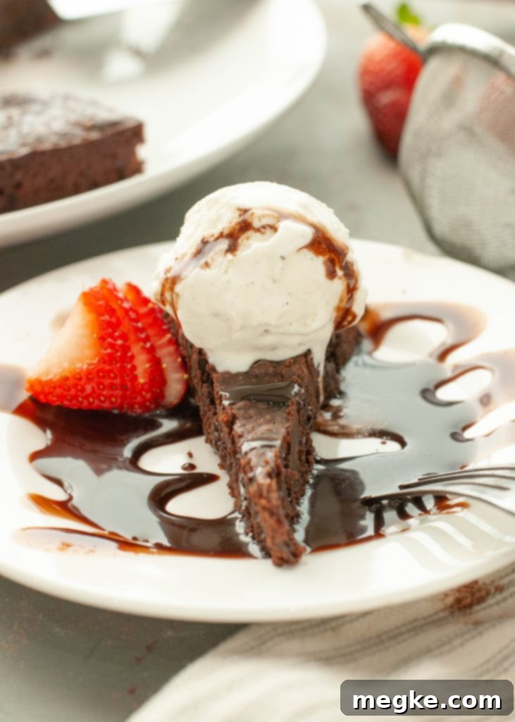 flourless-chocolate-torte-with-ice-cream-and-chocolate-sauce-on-top-with-a-strawberry-next-to-it-straight-on