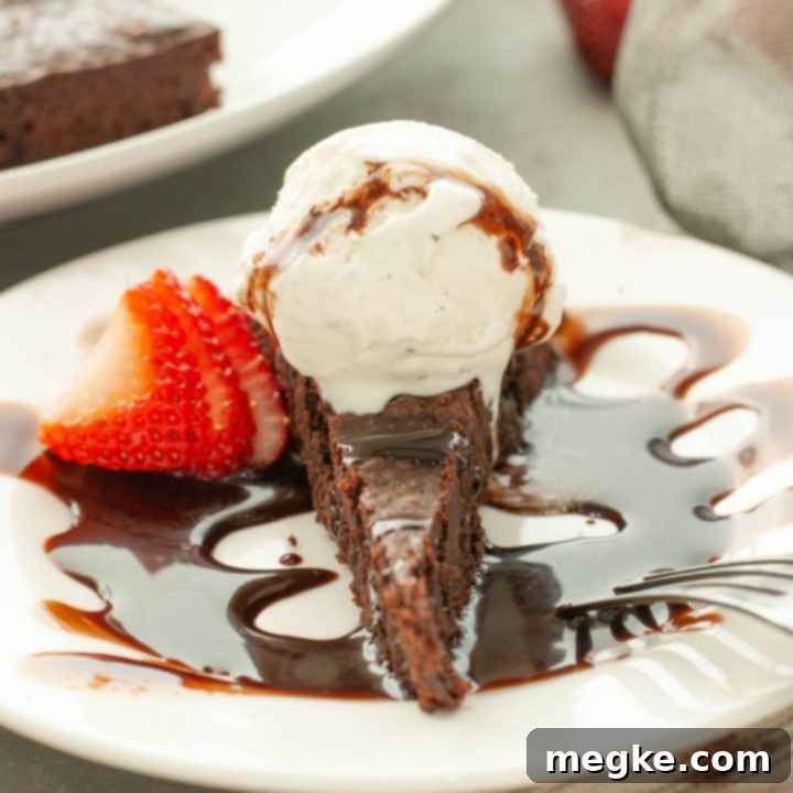 Easy Gluten Free Flourless Chocolate Torte Video Recipe 8 flourless-chocolate-torte-with-ice-cream-and-chocolate-sauce-on-top-with-a-strawberry-next-to-it-straight-on